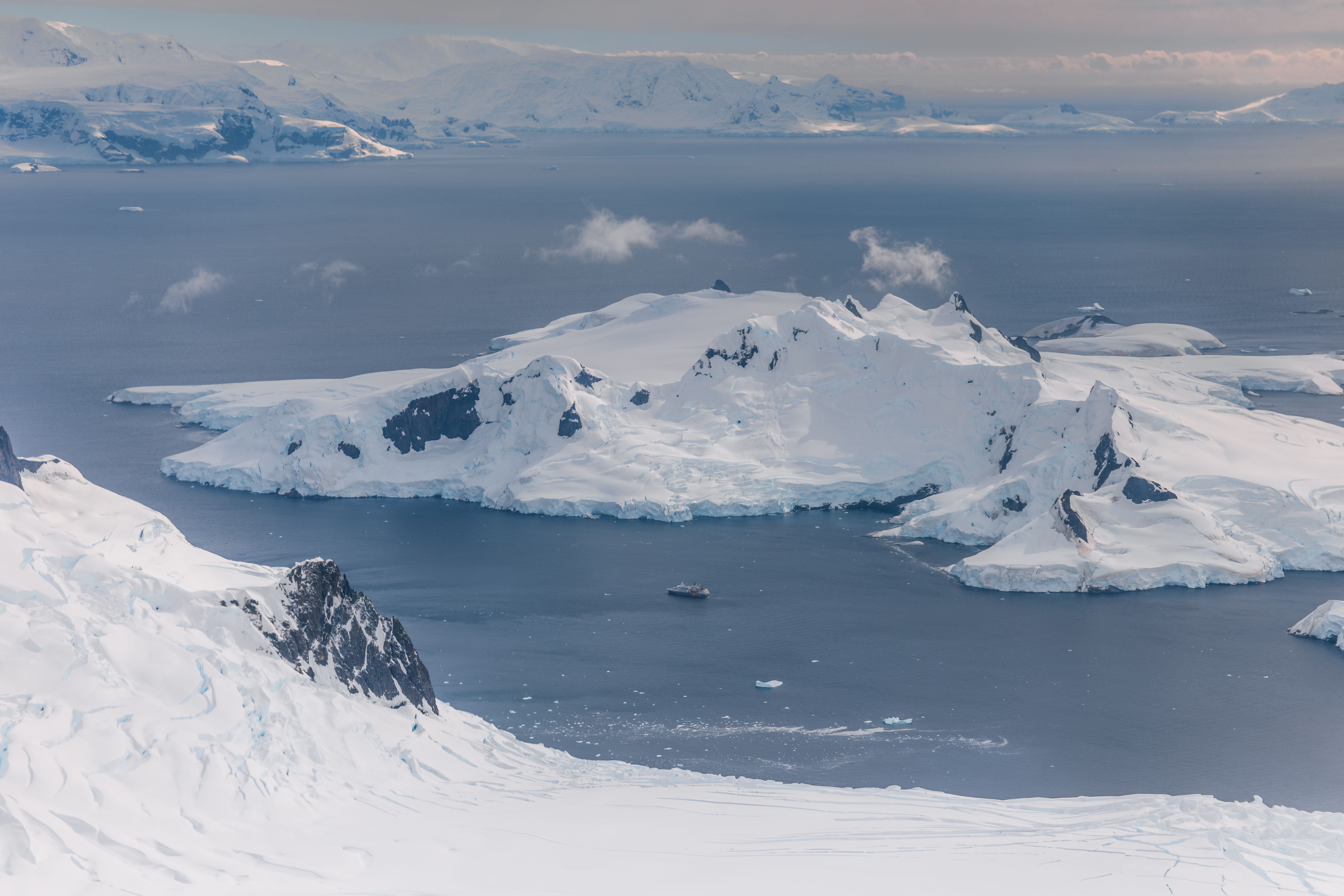 A wide view over snowy Antarctic islands and a calm bay